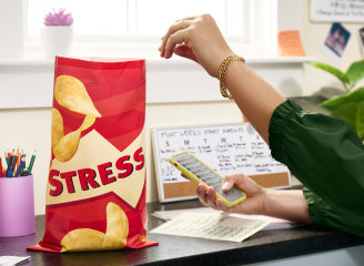 A bag of stress labeled chips on a desk with girl in green jacket emotional eating